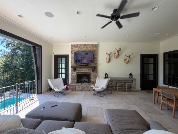 Covered patio/sunroom opening up to a pool view, featuring outdoor lounge furniture, a fireplace, and ceiling fan.